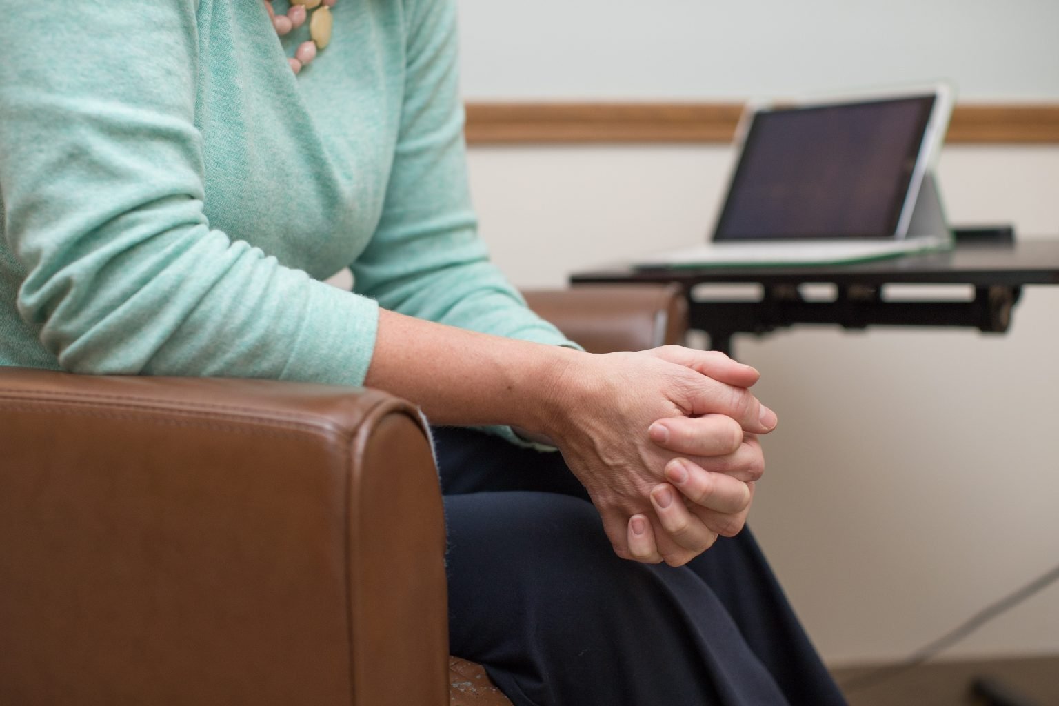 Close-up of clasped hands during an online therapy session with a tablet visible in Columbus, Ohio