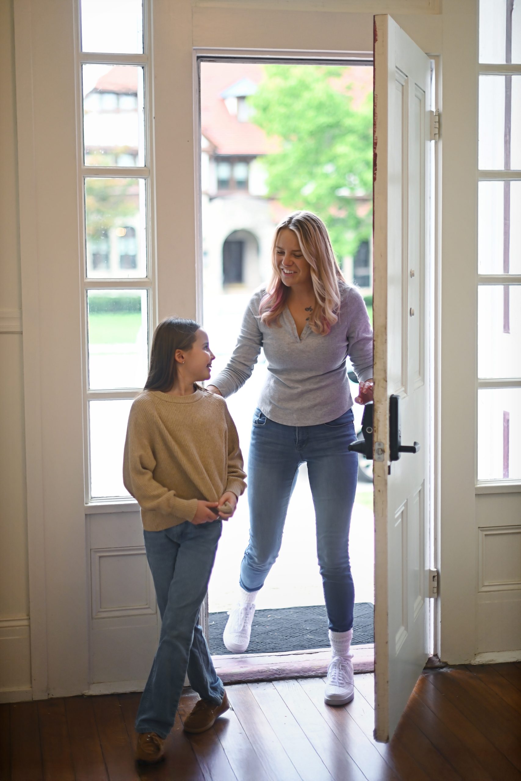 Therapist welcoming a smiling girl through the front door of Holistic Consultation in Troy, Ohio