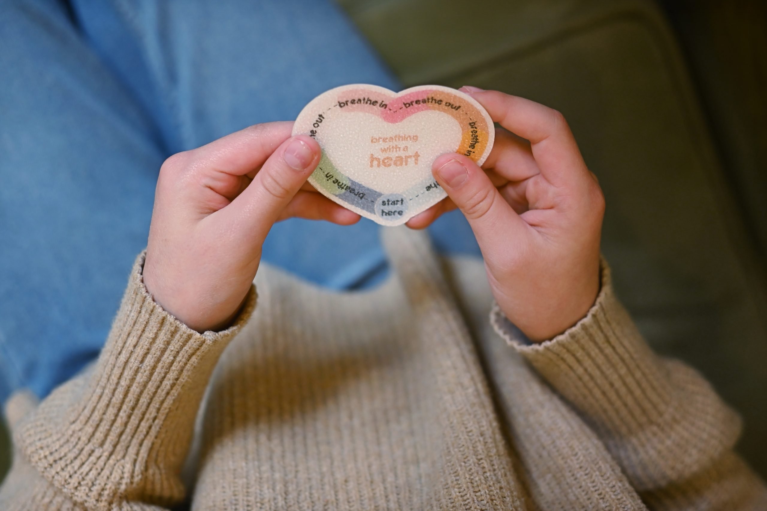 Hands holding a heart-shaped breathing card, a simple calming tool families can use at home
