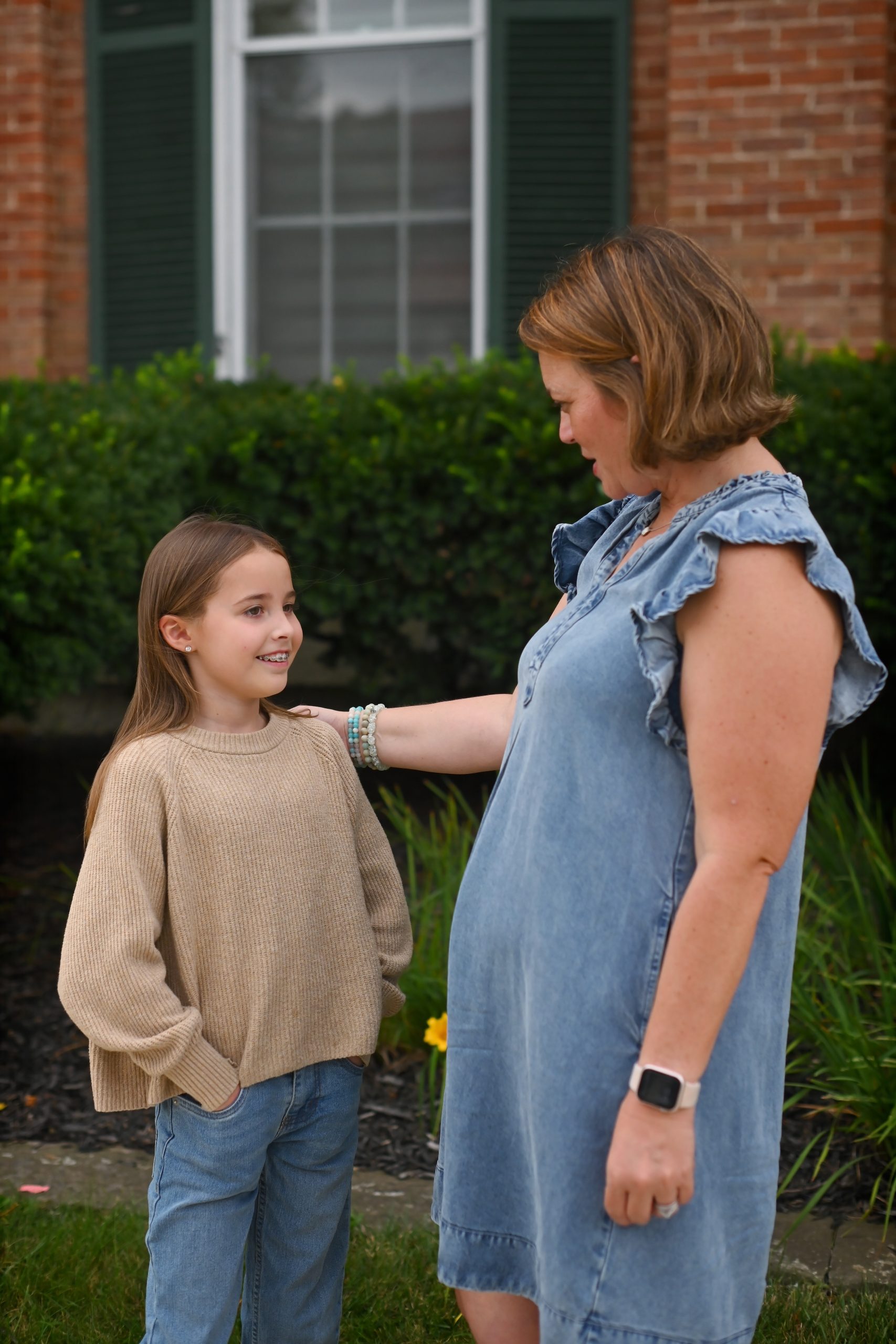 Adult resting a reassuring hand on a smiling girl's shoulder outside a family therapy office in Troy, Ohio