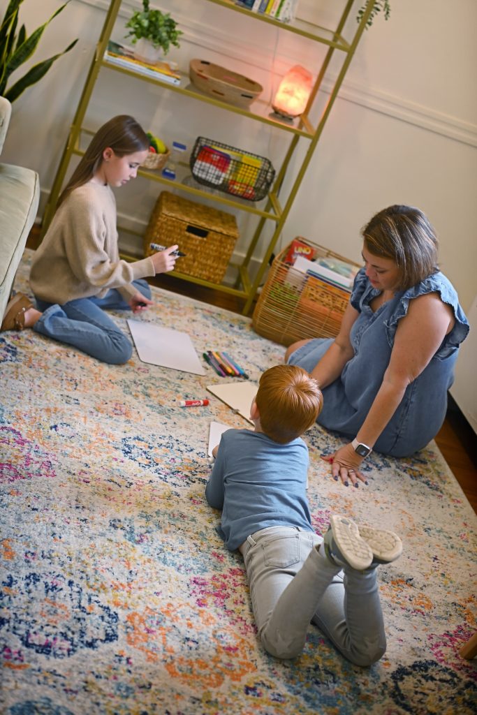Therapist sitting on the floor drawing on whiteboards with a girl and a boy during play therapy in Troy, Ohio