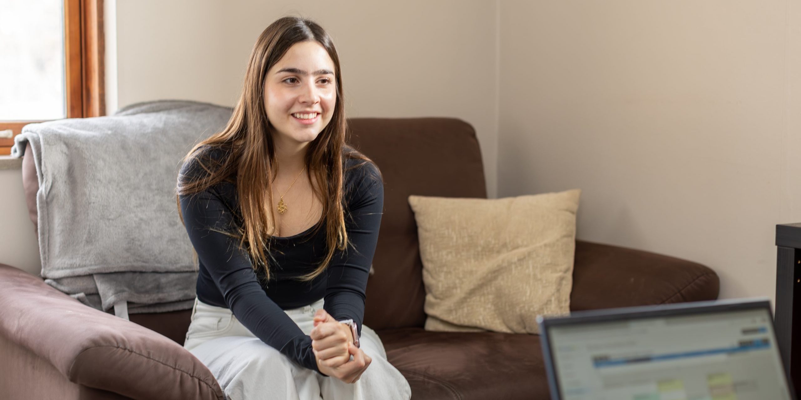 Woman relaxing on a couch at home while connecting with her therapist online through Holistic Consultation's telehealth services in Columbus, Ohio