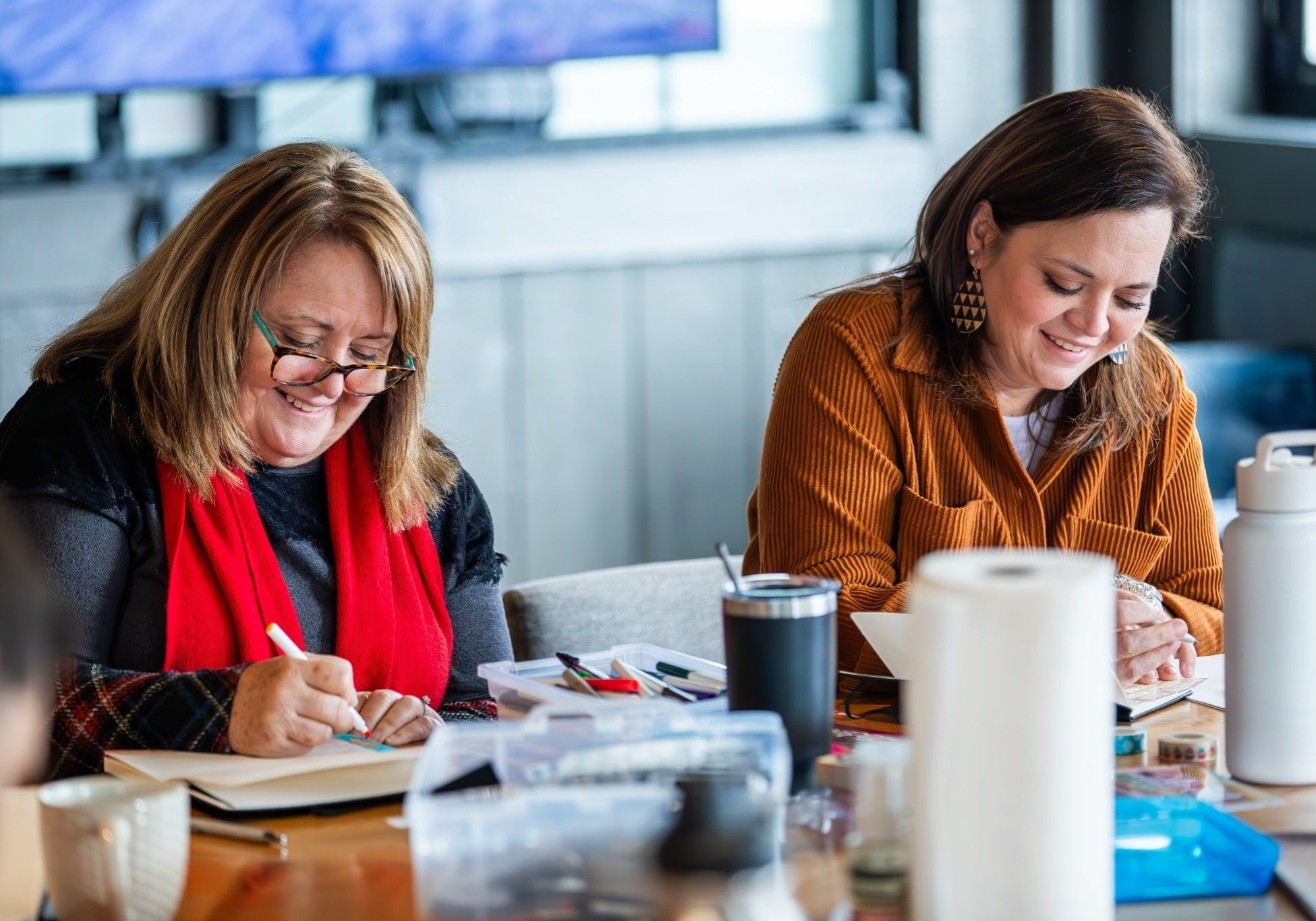 Two team members from Holistic Consultation smiling and journaling together during a creative team activity in Columbus, Ohio